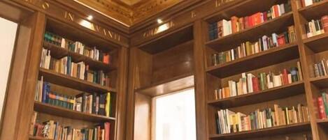 Una biblioteca con estanterías de madera, una mesa con sillas y un techo decorativo.