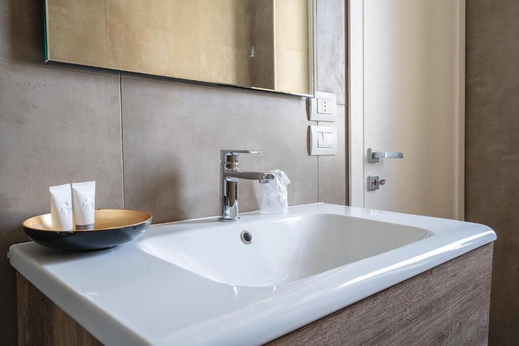 Een badkamer met een witte wastafel, een spiegel erboven en een houten wastafelmeubel.