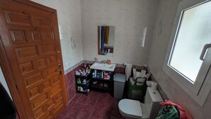 Une petite salle de bain avec une porte en bois, un lavabo, des toilettes et une fenêtre.