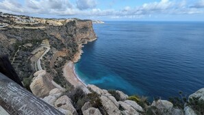 Un paysage côtier avec une route sinueuse, un terrain rocheux et une plage.