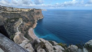 A coastal landscape with a winding road, rocky terrain, and a beach. - Detached house with panoramic views near the ocean (El Poble Nou de Benitatxell/Benitachell)