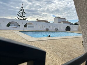 A swimming pool with a person swimming, surrounded by white buildings with arches and a clear sky. - Detached house with panoramic views near the ocean (El Poble Nou de Benitatxell/Benitachell)