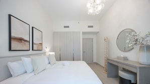 Un dormitorio moderno con cama, mesita de noche, espejo y una obra de arte en la pared.