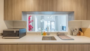 Una cocina moderna con armarios de madera, microondas integrado, un fregadero y un ventanal con vistas al exterior.