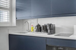 Una cocina con un lavamanos, una cafetera y un hervidor.