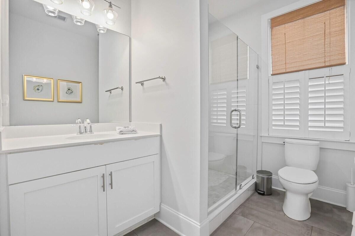 A bathroom with a white vanity, a glass shower enclosure, and a toilet.