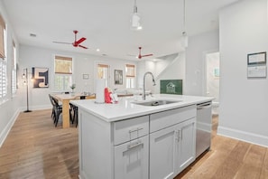 Una cocina moderna con armarios blancos, una isla central y un comedor con mesa y sillas.
