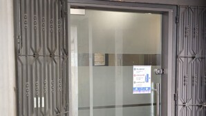 Entrada d'un hotel amb una porta de vidre, reixes metàl·liques, catifa vermella i un cartell que diu 'HOTEL ROYAL'.