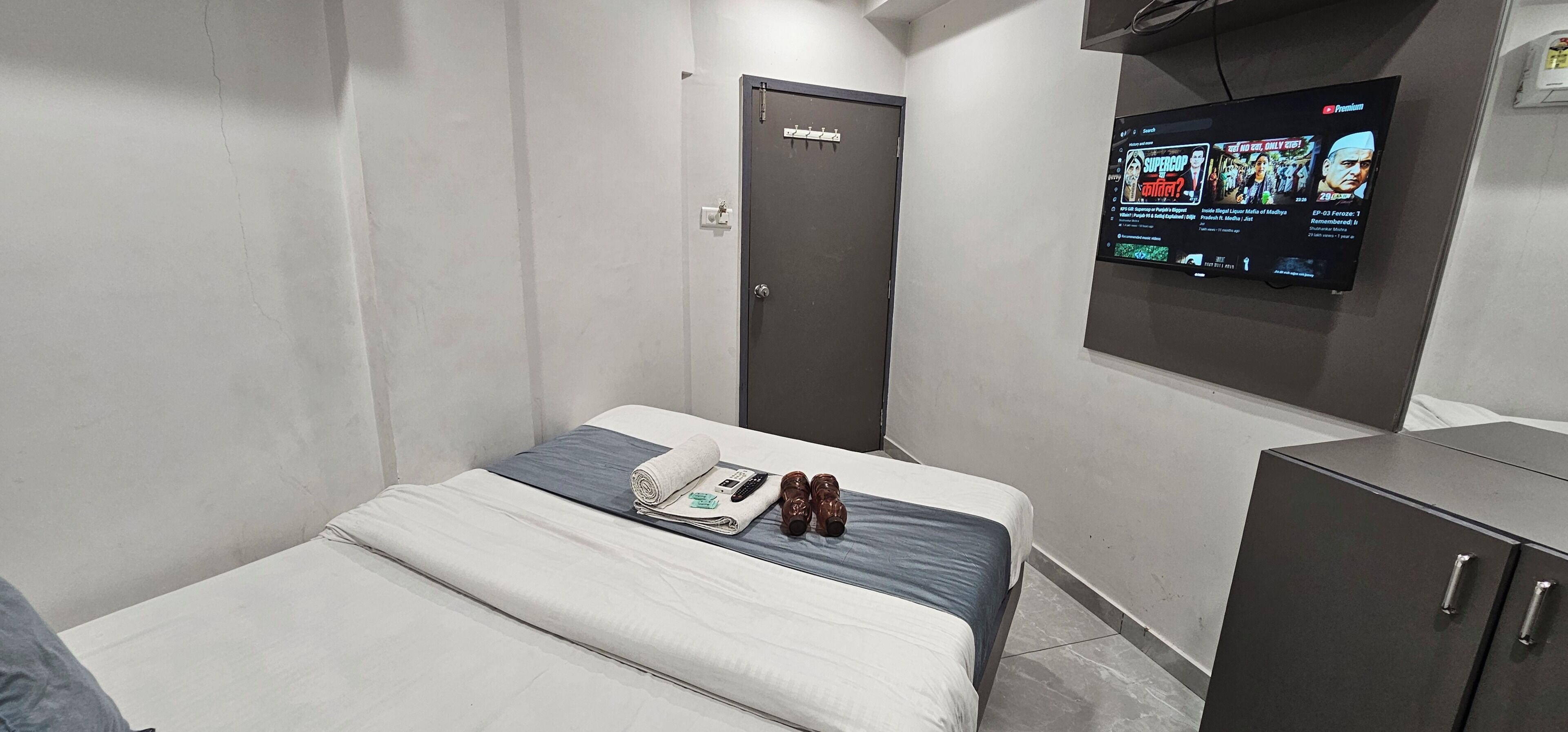 Una camera d'albergo con un letto, una TV a parete, un armadio e una porta.