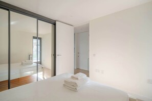 Ein modernes Schlafzimmer mit einem großen Bett, einer Schiebetür aus Glas und einem sichtbaren Badezimmer.