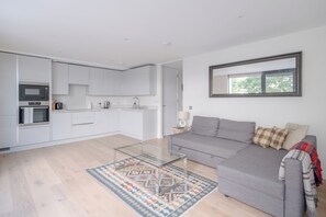A modern living space with a kitchen, a sofa, and a patterned rug. - 1BD City Retreat by the River Thames, Battersea (London)