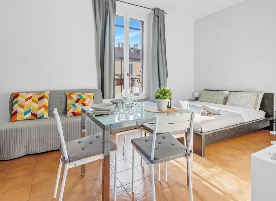 Eine moderne Wohnung mit Essbereich, Sofa, Bett und Blick auf die Stadt.