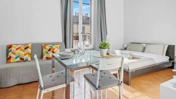 Eine moderne Wohnung mit Essbereich, Sofa, Bett und Blick auf die Stadt.