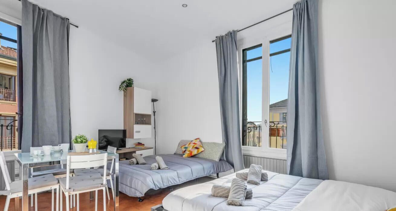 Ein modernes Hotelzimmer mit Bett, Schreibtisch, Sessel, Fernseher und einem Balkon mit Blick.