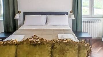Um quarto com uma cama, duas mesas de cabeceira, um sofá e vista para o exterior pela janela.