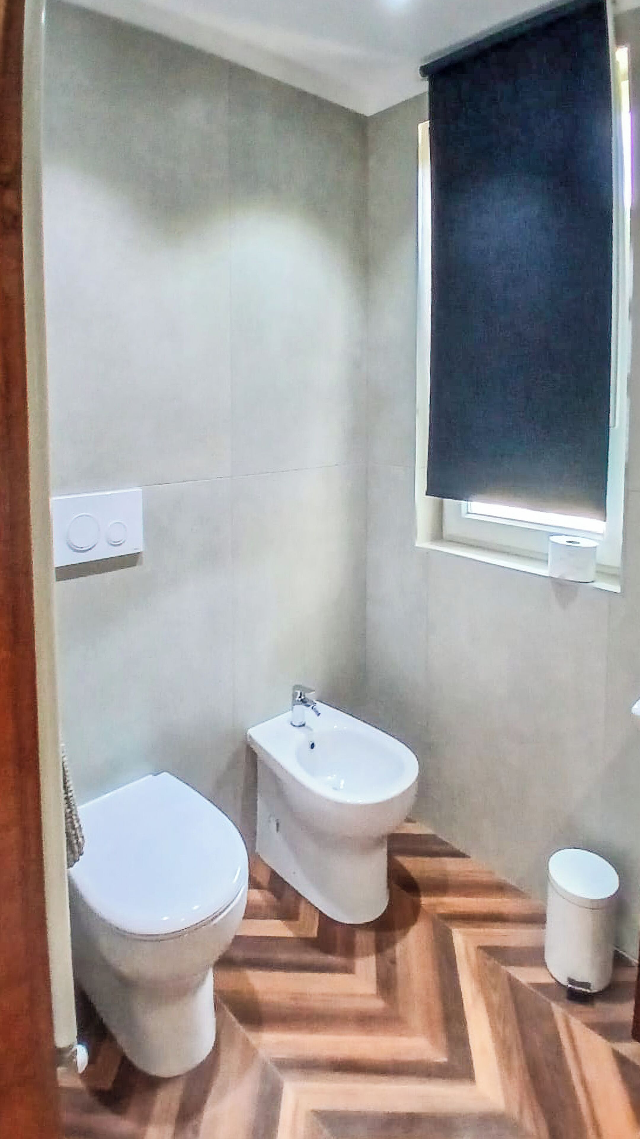 A bathroom with a toilet, bidet, and a small trash bin.