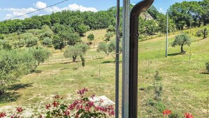 A balcony with potted plants and a view of a hilly landscape with trees and power lines.