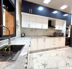 A modern kitchen with a marble countertop, stainless steel appliances, and a built-in oven.
