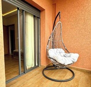 A room with a hanging chair, a sliding glass door, and a wooden floor. - Cosy villafor your stay (Marrakech)