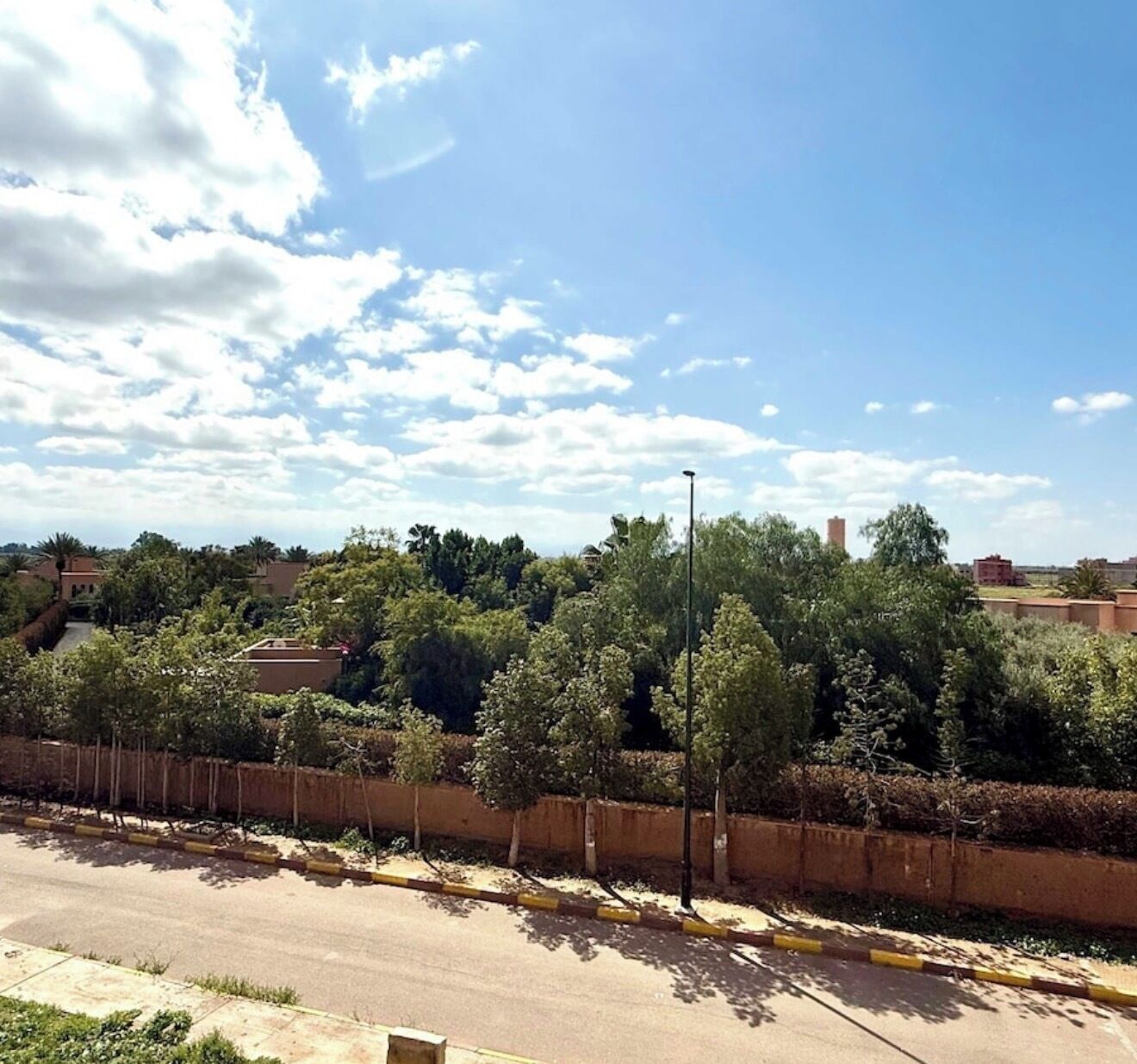 Un quartier résidentiel avec une route, une clôture et des arbres.
