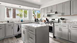 A modern kitchen with grey cabinets, a central island, a stove, and a microwave.