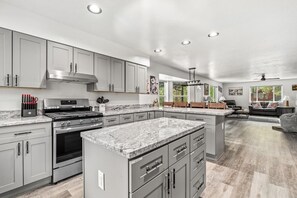 A modern kitchen with granite countertops, stainless steel appliances, and grey cabinetry. - Outdoor Firepit - Air Conditioning - Pool Table (Flagstaff)