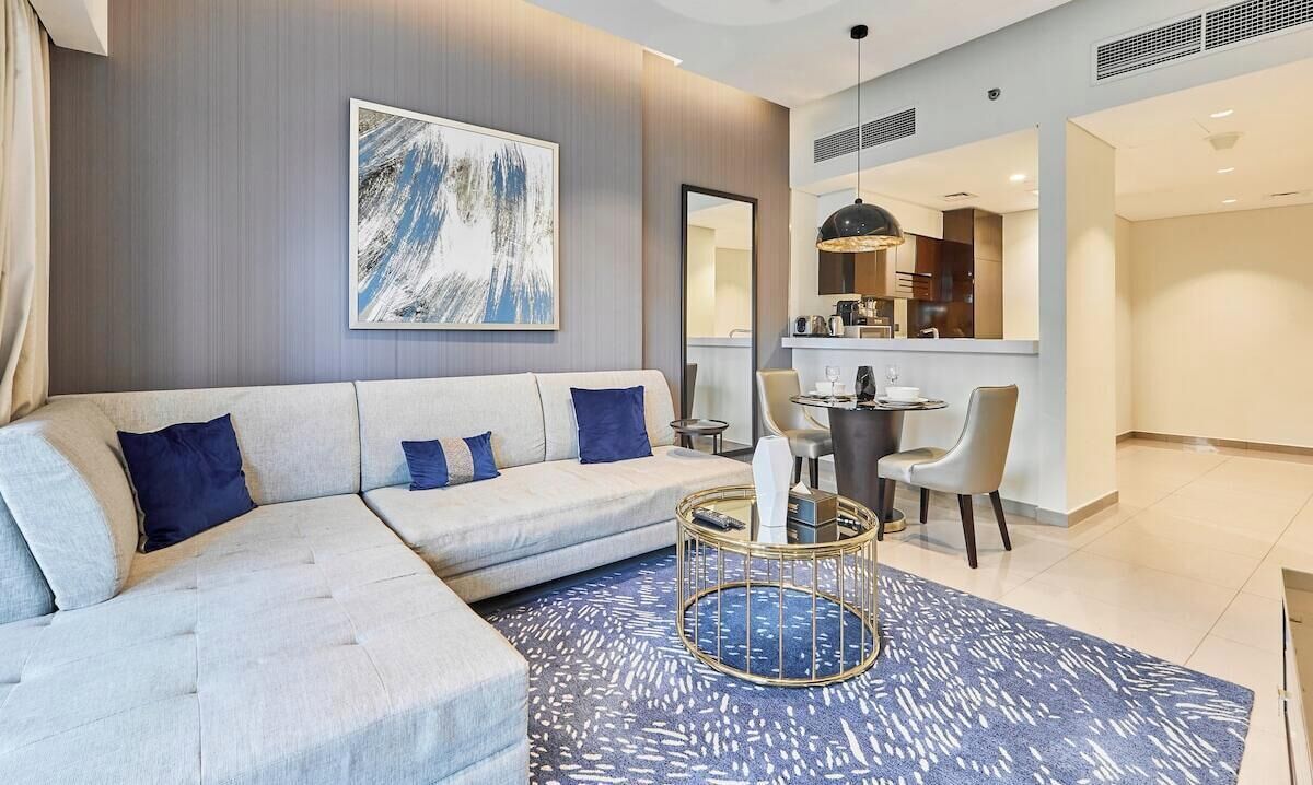 A modern living room with a sectional sofa, a coffee table, and a dining area with chairs and a table.