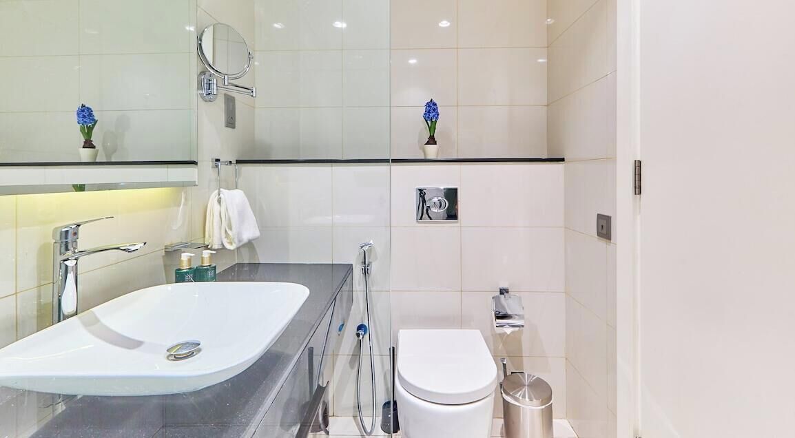 A modern bathroom with a white sink, mirror, and toilet.