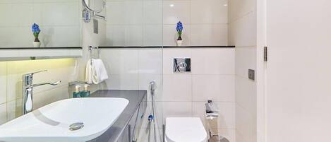 A modern bathroom with a white sink, mirror, and toilet.