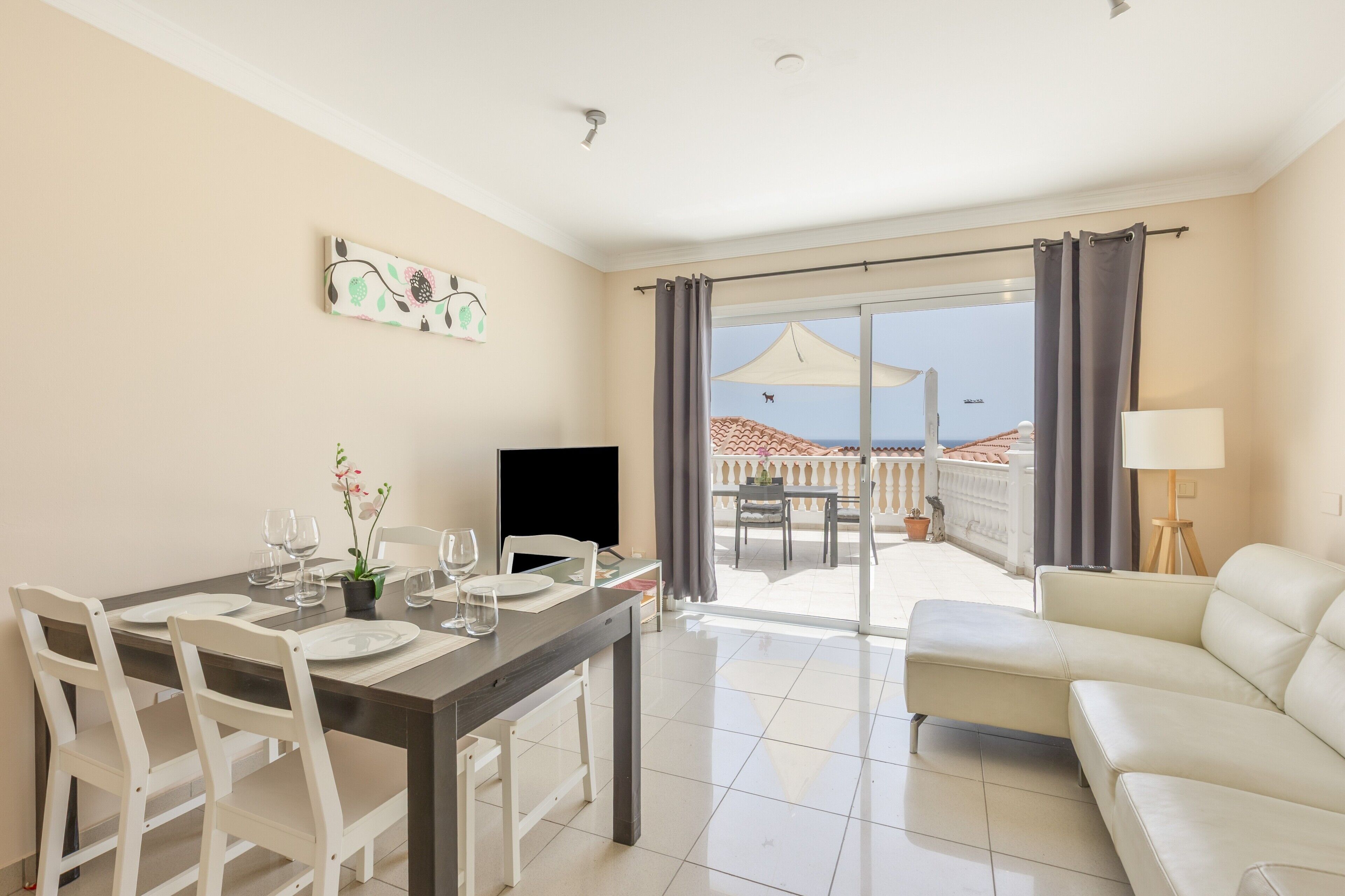A dining area with a table set for four, a TV, and a sofa.