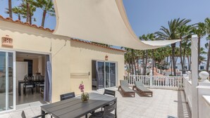 A patio with a table and chairs, a sliding glass door, and a white awning. - Casa Bella 1 - Apartment with Sea and Beach Views (Costa Calma)