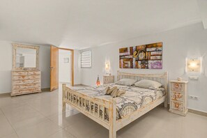 A bedroom with a wooden bed, a dresser, a mirror, and a wall-mounted light fixture. - Casa Bella 2 – 100 m² Apartment for Four Guests, 3 Minutes from the Beach (Costa Calma)