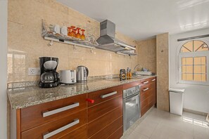 A kitchen with a granite countertop, stainless steel appliances, wooden cabinets, and a window with a view. - Casa Bella 2 – 100 m² Apartment for Four Guests, 3 Minutes from the Beach (Costa Calma)