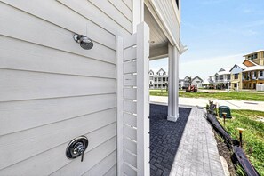 A house with a white exterior, a front door, and a brick pathway leading to a covered porch. - Tranquil 4-Bed Lakeside Home Steps from the Beach with Three King Suites (Port Aransas)
