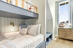 A bedroom with a bunk bed, a bedside table with a lamp, and a window with curtains. - Tranquil 4-Bed Lakeside Home Steps from the Beach with Three King Suites (Port Aransas)