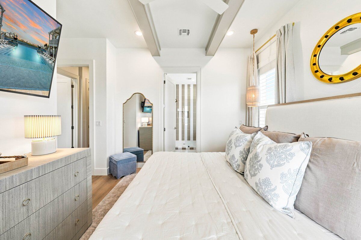 A bedroom with a bed, a dresser, a TV, and a mirror.