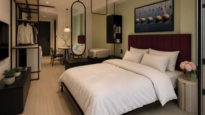 A modern hotel room with a large bed, a desk, a chair, a mirror, a bookshelf, and a television. - Centraltique Passage Living (Hanoi)