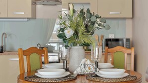 A dining table set with white plates, glasses, and a vase with flowers. - Spacious Apartment with a Balcony | Parking | 2 Bedrooms (Toruń)