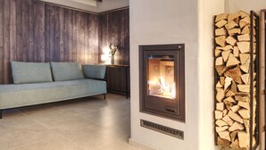 Un soggiorno moderno con un divano, un camino, pannelli murali in legno e una pila di legna da ardere.