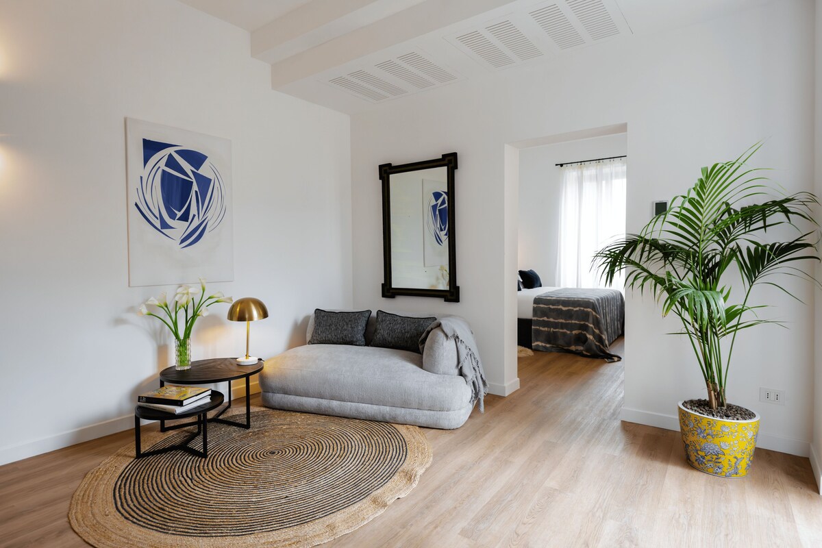 A modern living room with a sofa, a coffee table, a potted plant, and artwork on the walls.