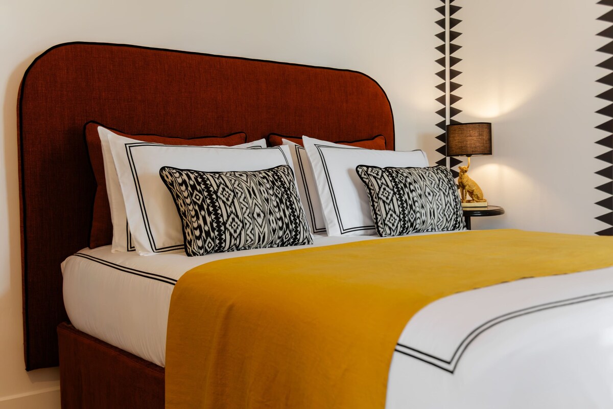 A bed with a wooden headboard, white bedding, and patterned pillows.
