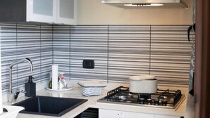 Ett kök med randigt stänkskydd, en gasspis, en diskho och skåp.