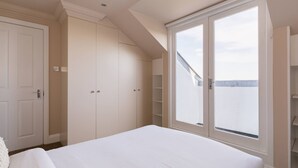 A bedroom with a large bed, a wardrobe, and a window with a view. - The Steele Blue House (London)