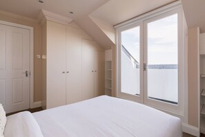 Ein Schlafzimmer mit einem großen Bett, einem Kleiderschrank und einem Fenster mit Blick.