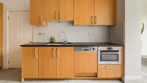 A modern kitchen with wooden cabinets, a black countertop, a Bosch dishwasher, and an oven. - The Steele Blue House (London)