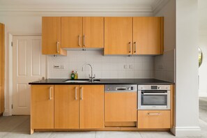Eine moderne Küche mit Holzausstattung, einer schwarzen Arbeitsplatte, einem Geschirrspüler von Bosch und einem Backofen.