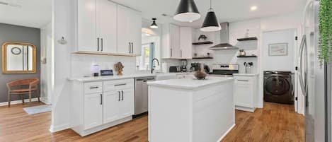 A modern kitchen with white cabinetry, a central island, and a built-in washing machine.