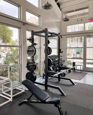 A gym with weightlifting equipment, large windows, and a bench. - The Tranquil Token-hot Tub & Ping Pong Table (North Charleston)