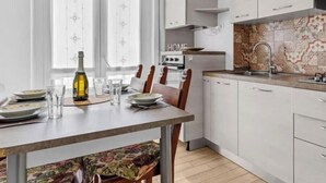 Una cucina moderna con mobili bianchi, un tavolo da pranzo per quattro persone e uno schienale decorato.