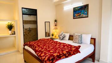 Una camera da letto con un letto, un comodino, uno specchio, un quadro e un angolo doccia.